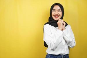 Beautiful young asian muslim woman confident and cheerful looking empty space presenting something, isolated on yellow background photo