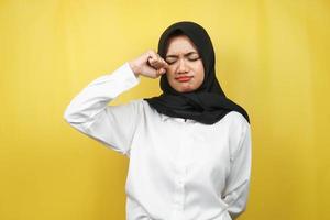 Beautiful young muslim woman crying, hands wiping tears, isolated on yellow background