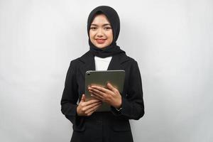 Beautiful young asian muslim business woman confident and smiling, with hands holding tablet, time to work, productive time, isolated on gray background