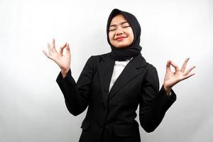 Hermosa joven mujer de negocios musulmana con las manos meditando signo, sonriendo cómodo y feliz, aislado sobre fondo blanco. foto
