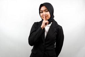 Beautiful asian young muslim business woman with finger on mouth, telling to be quiet, don't make noise, lower your voice, don't talk, isolated on white background photo