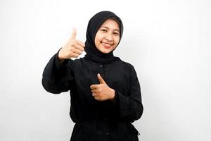 Beautiful young asian muslim woman smiling confident, enthusiastic and cheerful with hands thumbs up, ok sign, success, good job, success sign, isolated on white background photo