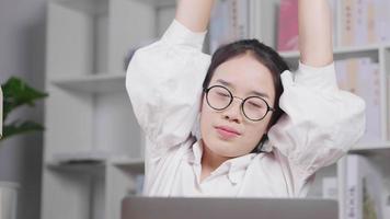 jeune femme asiatique travaillant sur un ordinateur portable et se reposant, levant les mains, faisant des étirements et retournant au travail. avoir sa propre entreprise. concept de travail à domicile video