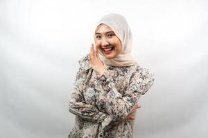 Beautiful young asian muslim woman smiling confidently and excitedly close to camera, whispering, telling secrets, speaking quietly, silent, isolated on white background