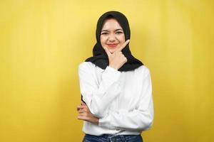 Beautiful young asian muslim woman smiling confident, enthusiastic and cheerful with hands V sign on chin isolated on yellow background