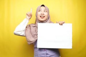 Pretty young muslim woman getting idea, hand holding blank empty banner, placard, white board, blank sign board, white advertisement board, presenting something in copy space, promotion photo