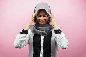 Beautiful young asian muslim woman shocked, dizzy, stressed, unhappy, many problems, want solution, with  hands holding head isolated on pink background photo