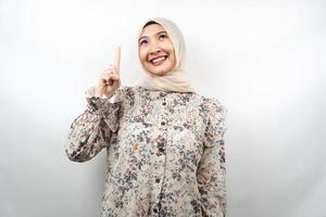 Hermosa joven musulmana asiática sonriendo confiada, entusiasta y alegre con las manos apuntando hacia arriba, obteniendo ideas, proponiendo soluciones, presentando algo, aislado sobre fondo blanco. foto