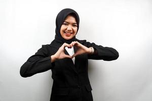 Beautiful asian young muslim business woman smiling confident, enthusiastic and cheerful with hands sign of love, affection, happy, on chest isolated on white background photo