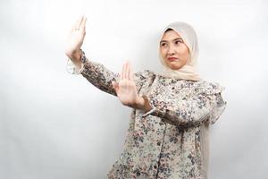Hermosa joven musulmana asiática con la mano rechazando algo, la mano deteniendo algo, disgustando algo en el espacio vacío, aislado sobre fondo blanco.