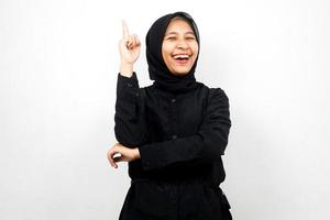 Beautiful and cheerful young asian muslim woman, pointing up, getting ideas isolated on white background photo