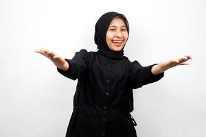 Hermosa y alegre joven mujer musulmana asiática, con los brazos abiertos, bienvenida, presentando algo alegremente, aislado sobre fondo blanco.
