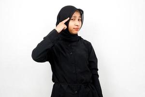 Hermosa joven mujer musulmana asiática con el dedo apuntando a la cabeza, pensando en forma inteligente, aislado sobre fondo blanco. foto