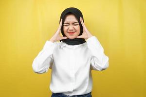 Hermosa joven musulmana asiática conmocionada, mareada, estresada, infeliz, con muchos problemas, quiere solución, con las manos sosteniendo la cabeza aislada sobre fondo amarillo