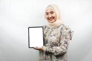 Beautiful young asian muslim woman smiling, excited and cheerful holding tablet with white or blank screen, promoting app, promoting product, presenting something, isolated on white background photo