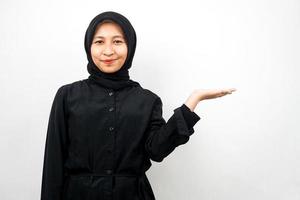 Beautiful young asian muslim woman with hands showing and presenting something in the direction of empty space, smiling confidently, excitedly, facing the camera, isolated on white background photo