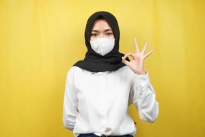 mujer musulmana con máscaras blancas, movimiento contra el virus corona, movimiento anti covid-19, movimiento de salud con máscaras, con las manos mostrando el signo de ok, buen trabajo, éxito, victoria, aislado
