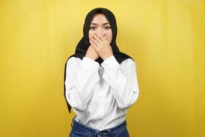 Beautiful young asian muslim woman shocked, surprised, disbelieving, getting shocking information, with hands covering mouth isolated on yellow background photo