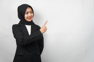 Beautiful young asian muslim business woman confident and smiling, with hands pointing to empty space, presenting something, presenting product, presenting report, isolated on gray background photo