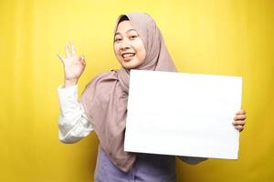 Pretty young muslim woman cheerful holding blank empty banner, placard, white board, blank sign board, white advertisement board, presenting something in copy space, promotion photo