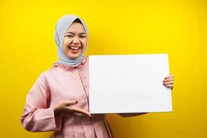 Pretty young muslim woman cheerful holding blank empty banner, placard, white board, blank sign board, white advertisement board, presenting something in copy space, promotion photo