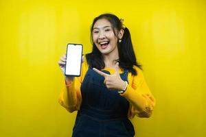 Pretty and cute young woman cheerful, confident, hands holding smartphone, with blank or white screen smartphone, promoting app, promoting product, advertisement, isolated photo