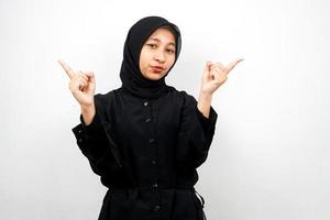 Beautiful asian young muslim woman with mouth watering, hand pointing at empty space presenting something, isolated on white background photo
