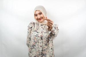 Beautiful young asian muslim woman smiling, with korean love sign hand, hand close to camera, isolated on white background photo