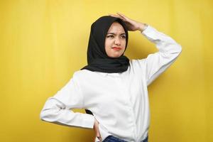 Hermosa joven musulmana asiática estresada, mareada, tiene un problema, se siente deprimida, con las manos sosteniendo la cabeza aislada sobre fondo amarillo