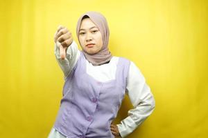 Beautiful young asian muslim woman pouting, belittling, disappointed, dissatisfied, not good, bad job, lousy, weak, looking at camera isolated on yellow background photo