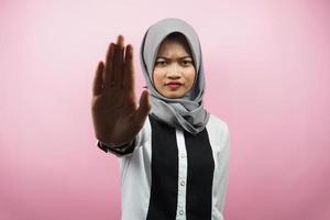Hermosa joven musulmana asiática con la mano de la señal de pare, rechazar la mano de la señal, mano de la señal de prohibición, no acercarse a la mano, mantenerse alejado de la mano del signo, no mover la mano del signo, aislado sobre fondo rosa foto