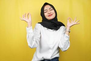 Hermosa joven musulmana con las manos meditando signo, sonriendo cómodo y feliz, aislado sobre fondo amarillo