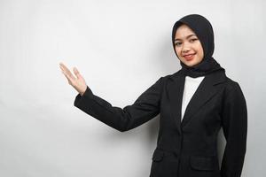 Hermosa joven mujer de negocios musulmana asiática confiada y sonriente, con los brazos abiertos, presentando algo, presentando un producto, presentando un informe, aislado sobre fondo gris foto