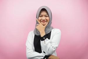 Beautiful young asian muslim woman smiling confident, enthusiastic and cheerful with hands V sign on chin isolated on pink background photo