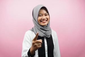 Beautiful young asian muslim woman smiling confident and cheerful, with hands pointing at camera, pointing at audience, pointing to customer, isolated on pink background