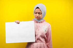 Bastante joven mujer musulmana triste, mano sosteniendo pancarta vacía en blanco, cartel, tablero blanco, tablero de letrero en blanco, tablero de anuncio blanco, presentando algo en el espacio de la copia, promoción foto