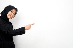 Hermosa joven mujer musulmana asiática con las manos apuntando al espacio vacío, presentando algo, aislado sobre fondo blanco. foto