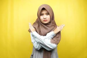Hermosa joven musulmana asiática con brazos cruzados, manos mostrando rechazo, manos mostrando prohibición, manos mostrando desaprobación, aislado sobre fondo amarillo