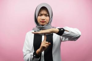 Beautiful asian young muslim woman with hand showing stop sign, silent sign hand, do not speak sign hand, do not make noise sign hand, isolated on pink background photo