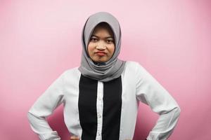 Beautiful young asian muslim woman pouting, angry, feeling annoyed, dissatisfied, uncomfortable, feeling bullied, lied to, looking at camera isolated on pink background photo