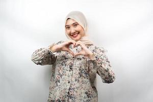 Beautiful asian young muslim woman smiling confident, enthusiastic and cheerful with hands sign of love, affection, happy, on chest isolated on white background