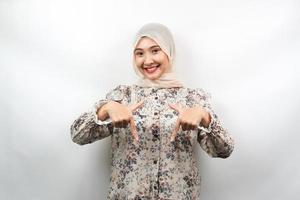 Beautiful asian young muslim woman with hands pointing down, hands click the link below, hands presenting something, isolated on white background photo