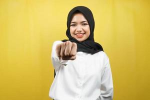 Hermosa joven musulmana asiática sonriendo confiada, entusiasta y alegre con los puños apretados a la cámara, puñetazos, peleas, cooperación, ojos brillantes, mirando a cámara aislada foto