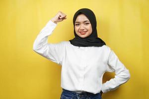 Beautiful asian young muslim woman with raised muscles, strength sign arms, isolated on yellow background photo