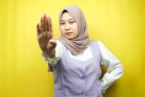 Hermosa mujer musulmana joven asiática con la mano de la señal de pare, rechazar la mano de la señal, mano de la señal de prohibición, no acercarse a la mano, mantenerse alejado de la mano del signo, no mover la mano del signo, aislado sobre fondo amarillo foto