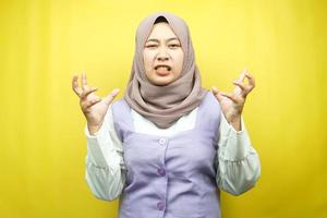 Joven y bella mujer musulmana asiática conmocionada, mareada, estresada, infeliz, con muchos problemas, quiere una solución, con las manos arriba aisladas sobre fondo amarillo foto
