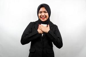 Hermosa joven mujer de negocios musulmana asiática sonriendo sorprendida y alegre, con las manos sosteniendo el pecho, emocionada, sin esperar, mirando a cámara aislada sobre fondo blanco foto