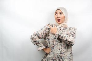 Beautiful young asian muslim woman shocked, surprised, wow expression, with hand pointing to empty space, presenting something, presenting product, isolated on white background
