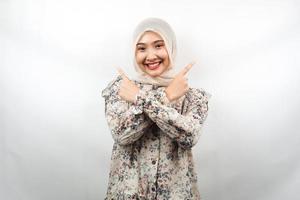 Beautiful young asian muslim woman smiling confident, enthusiastic, cheerful with hands pointing  empty space presenting something, looking at camera isolated on white background, advertising concept photo