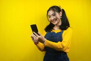 Pretty and cute young woman cheerful, confident, with hands holding smartphone, promoting product, presenting something, advertisement, isolated photo